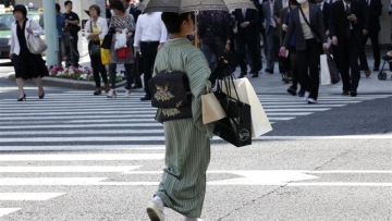 A woman in a traditional "Kimono" carries shopping bags at a shopping district in Tokyo