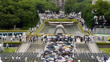 People wait in queue to offer prayers for the victims of the 1945 atomic bombing, in the rain at the Peace Memorial Park in Hiroshima