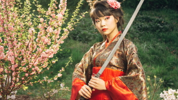Beautiful geisha in kimono with samurai sword