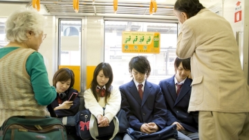high scool student sitting on priority seat of train