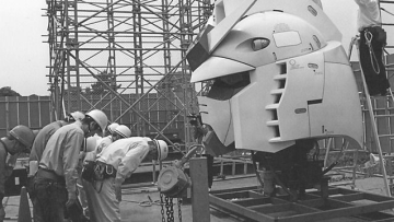 Pekerja konstruksi memberi hormat pada kepala patung Gundam