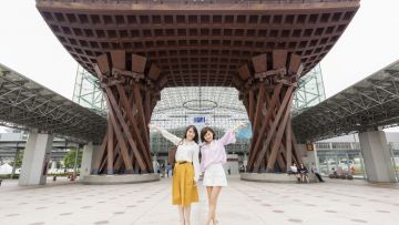 Dua wanita berfoto di depan Tsuzumimom Gate Stasiun Kanazawa, stasiun terindah di dunia