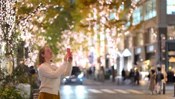 Seorang wanita yang sedang memotret pemandangan di Jalan Marunouchi Seorang wanita yang sedang memotret pemandangan di Jalan Marunouchi