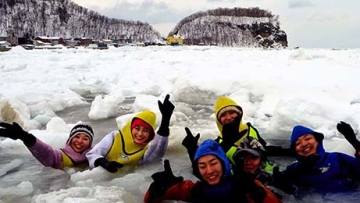 Para wisatawan yang mengenakan drysuit berenang di perairan laut es di Shari, Hokkaido, pada tanggal 8 Februari (Masatoshi Narayama)