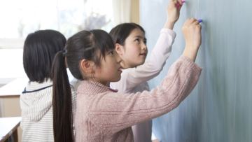 黒板に絵を描く小学生女孁E