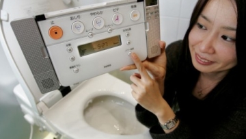 Toto employee Kumi Goto demonstrates its new toilet seat from the "New Neorest" series in Tokyo.