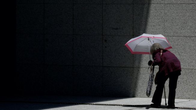 Seorang wanita tua membawa payung masuk ke sebuah gedung komersial di Tokyo. REUTERS, Kim Kyung-Hoon