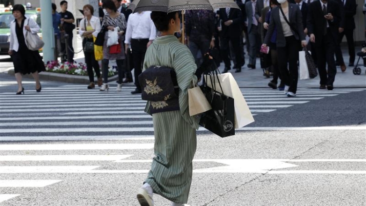 A woman in a traditional "Kimono" carries shopping bags at a shopping district in Tokyo