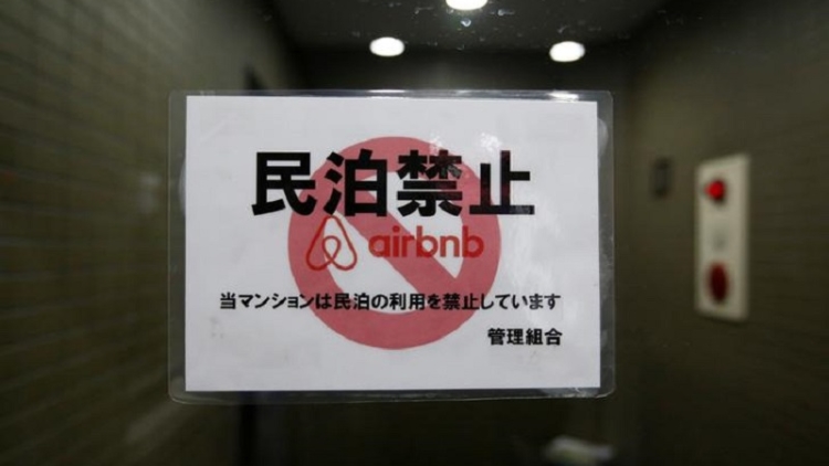a-sign-communicating-the-ban-on-using-the-apartment-building-as-airbnb-service-by-the-building-management-is-attached-to-the-buildings-front-door-in-tokyo-japan a-sign-communicating-the-ban-on-using-the-apartment-building-as-airbnb-service-by-the-building-management-is-attached-to-the-buildings-front-door-in-tokyo-japan