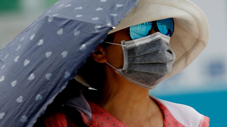 A woman uses a parasol on the street during a heatwave in Tokyo