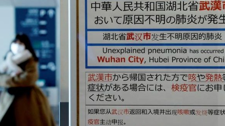 FILE PHOTO: A woman wearing a mask walks past a quarantine notice about the outbreak of coronavirus in Wuhan, China at an arrival hall of Haneda airport in Tokyo FILE PHOTO: A woman wearing a mask walks past a quarantine notice about the outbreak of coronavirus in Wuhan, China at an arrival hall of Haneda airport in Tokyo