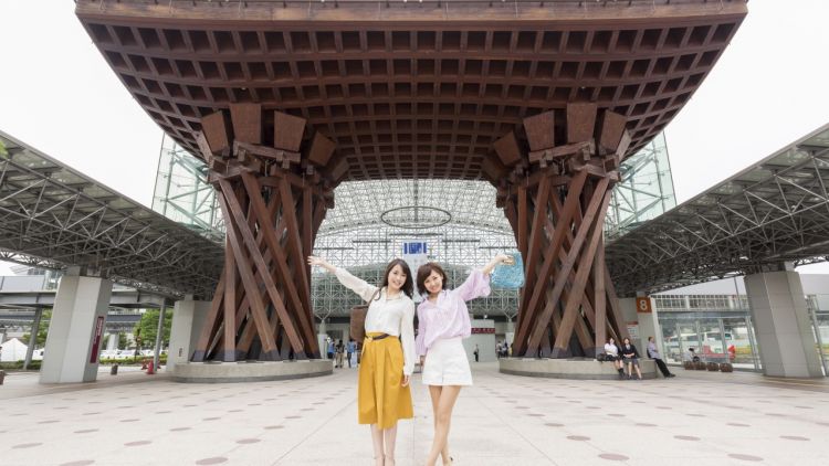 Dua wanita berfoto di depan Tsuzumimom Gate Stasiun Kanazawa, stasiun terindah di dunia