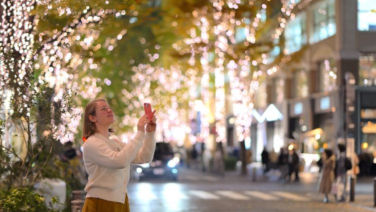 Seorang wanita yang sedang memotret pemandangan di Jalan Marunouchi