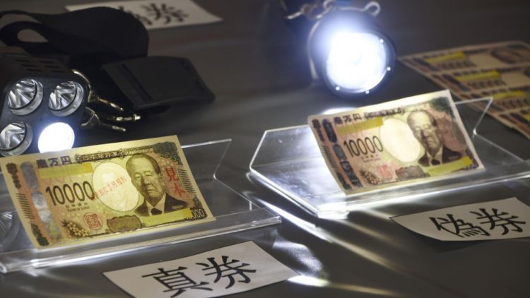 Polisi menggunakan lampu untuk menunjukkan perbedaan antara uang kertas baru Polisi menggunakan lampu untuk menunjukkan perbedaan antara uang kertas baru